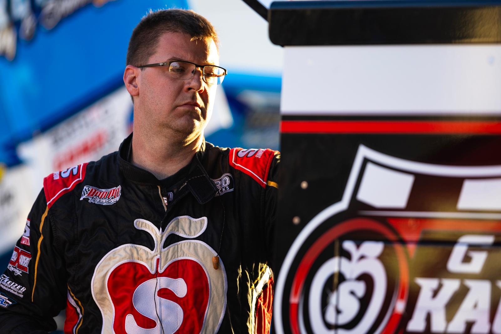 Sprint Car racer Danny Dietrich standing by his car in the pits at a race track.